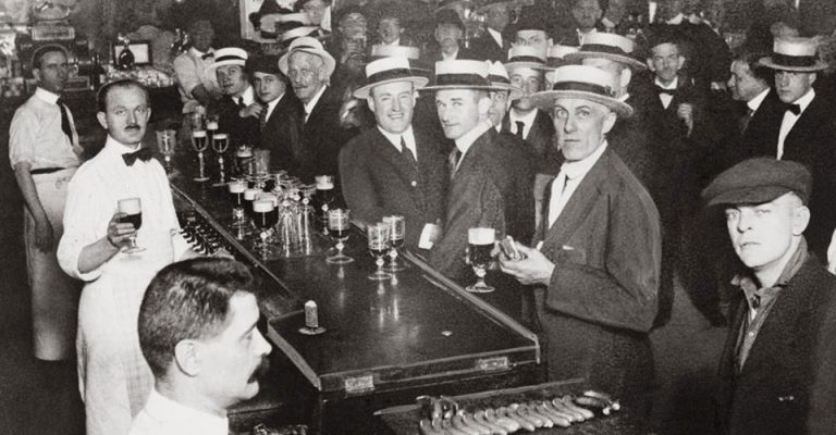 Vintage black & white photo of the interior of a crowded bar moments before midnight, June 30, 1919, when wartime prohibition went into effect, in New York City.
