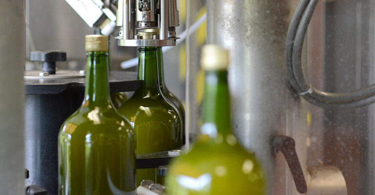 bottling line showing cap being place on a green bottle
