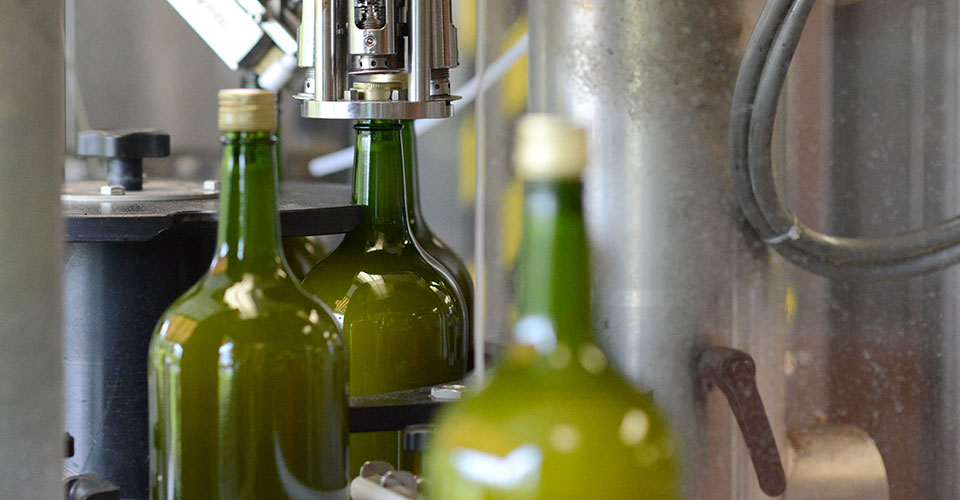 bottling line showing cap being place on a green bottle