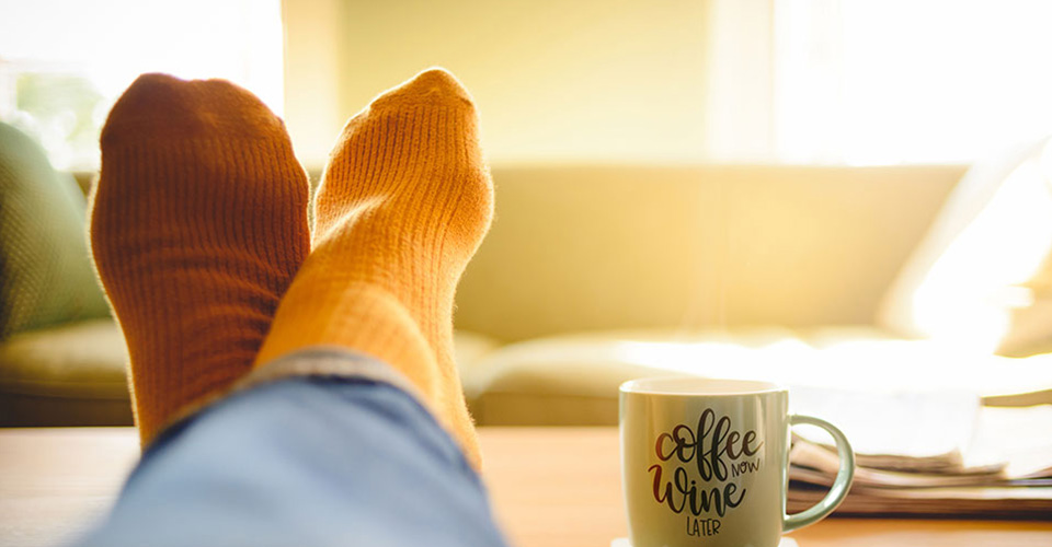 crossed feet up on a table with coffee cup