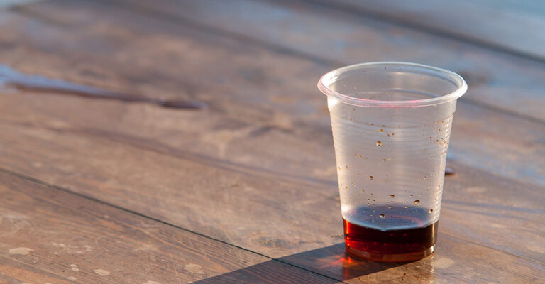 plastic cup with wine on wood table