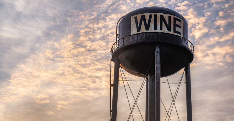 water tower with word "wine" against sunset sky