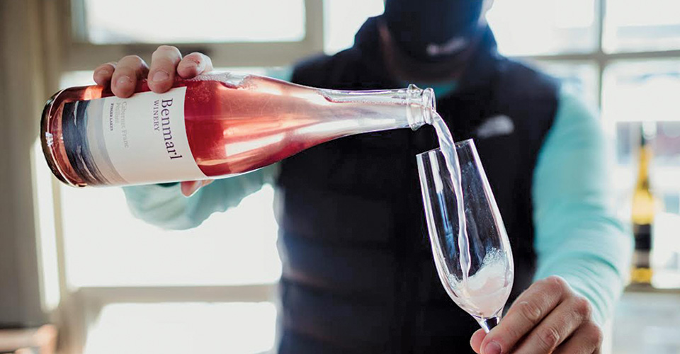 man pouring pink wine into glass