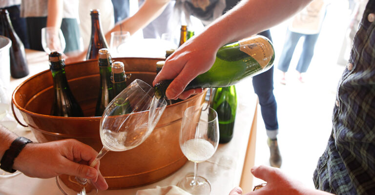 pouring cider into glass with bronze ice bucket in background